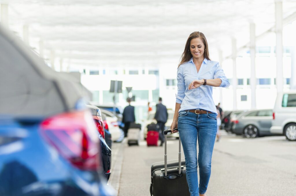 Smiling woman walking with luggage on parking lot